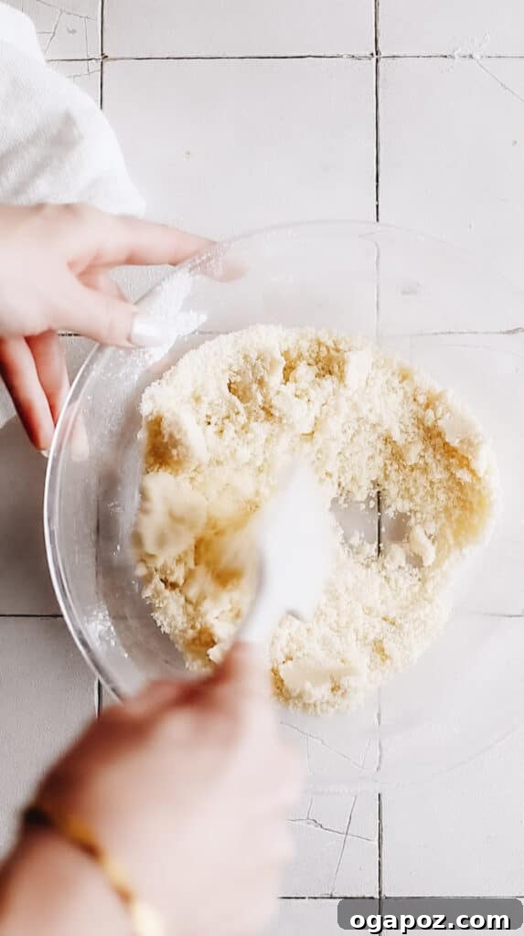 Snow Dusted Kourabiedes A Greek Christmas Classic 6 A spatula stirring the Kourabiedes dough in a mixing bowl, illustrating the cohesive and slightly crumbly texture of the reverse-creamed mixture just before shaping, a perfect consistency for these delicate Greek cookies.