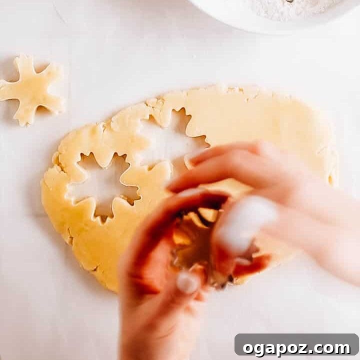 Sugar Snowflakes 7 Cutting out perfect snowflake shapes from rolled-out cookie dough using a cookie cutter.