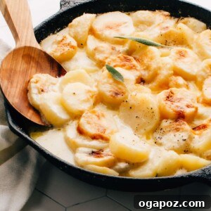 Gluten-free potatoes au gratin in a cast iron pan with serving spoon, showing the golden cheesy crust.