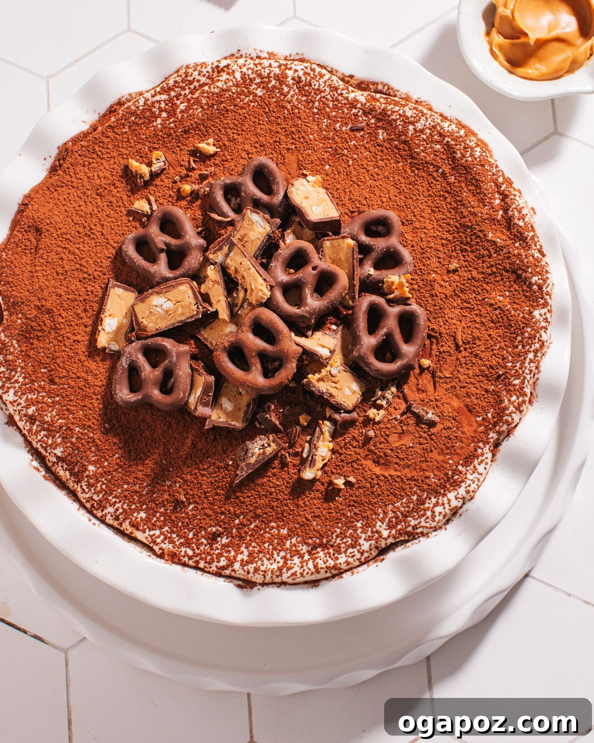 Effortless Chocolate Christmas Delights 17 A delectable Peanut Butter Pretzel Pie in a serving dish, topped with whipped cream and chocolate-covered pretzels.