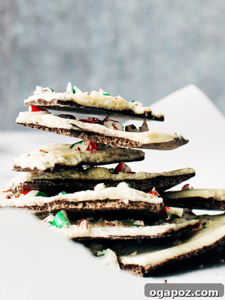 Effortless Chocolate Christmas Delights 26 A stack of colorful White Chocolate Candy Cane Christmas Bark pieces, featuring layers of white and dark chocolate with crushed candy canes.