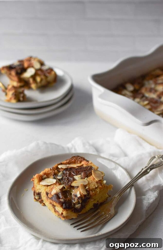 15 Italian Christmas Dessert Delights 11 A delectable portion of Panettone bread pudding, adorned with a light dusting of powdered sugar, served on a plate with a fork.