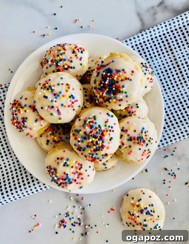15 Italian Christmas Dessert Delights 13 A stack of soft Italian ricotta cookies, glistening with frosting glaze and vibrant rainbow sprinkles, invitingly displayed.
