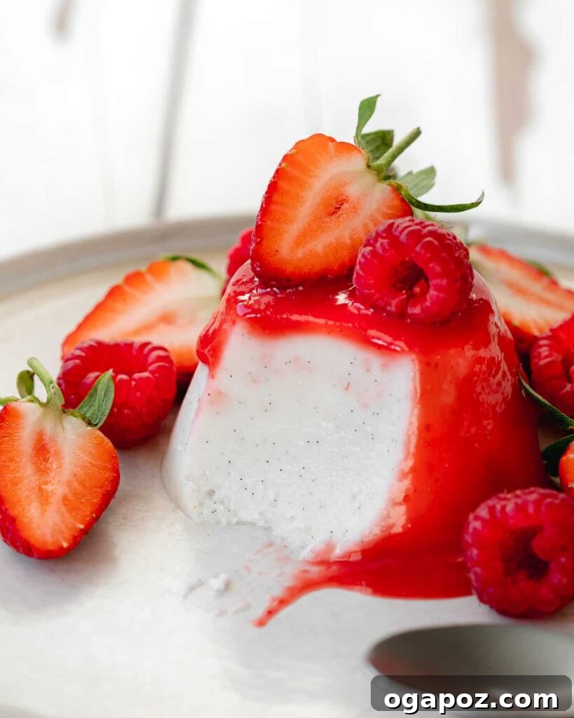 15 Italian Christmas Dessert Delights 14 A close-up view of traditional Italian panna cotta, elegantly garnished with vibrant strawberry coulis and fresh strawberries.
