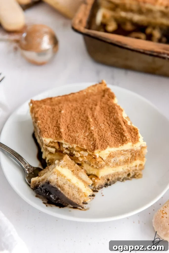 15 Italian Christmas Dessert Delights 15 A delectable piece of authentic Italian Tiramisu, artfully served on a plate with a fork, ready to be enjoyed.