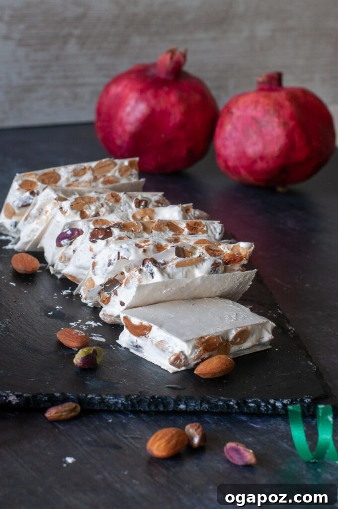 15 Italian Christmas Dessert Delights 7 Artfully arranged pieces of classic Italian nougat (Torrone), showcasing their light color and embedded nuts, on a dark surface.