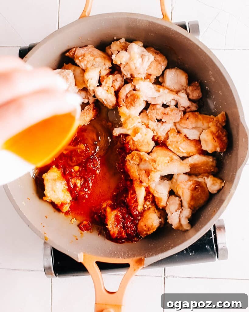 A close-up shot of honey being drizzled into the Gochujang chicken sauce during preparation.