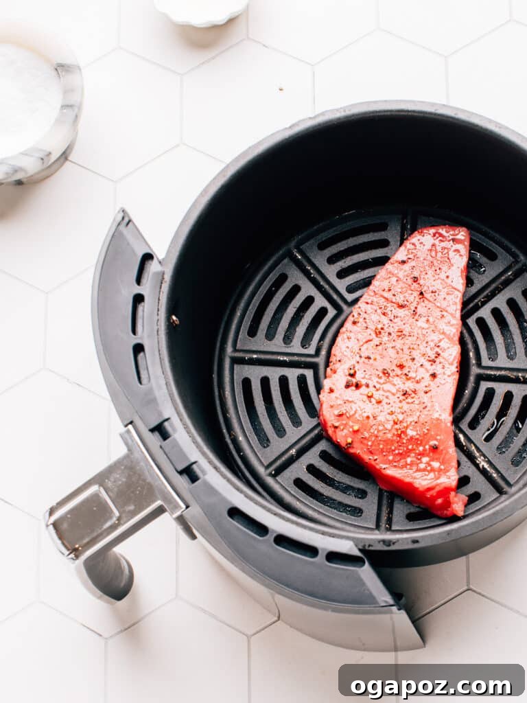Flawless Air Fryer Tuna Steaks 6 Raw ahi tuna steak in the air fryer basket with salt and pepper.