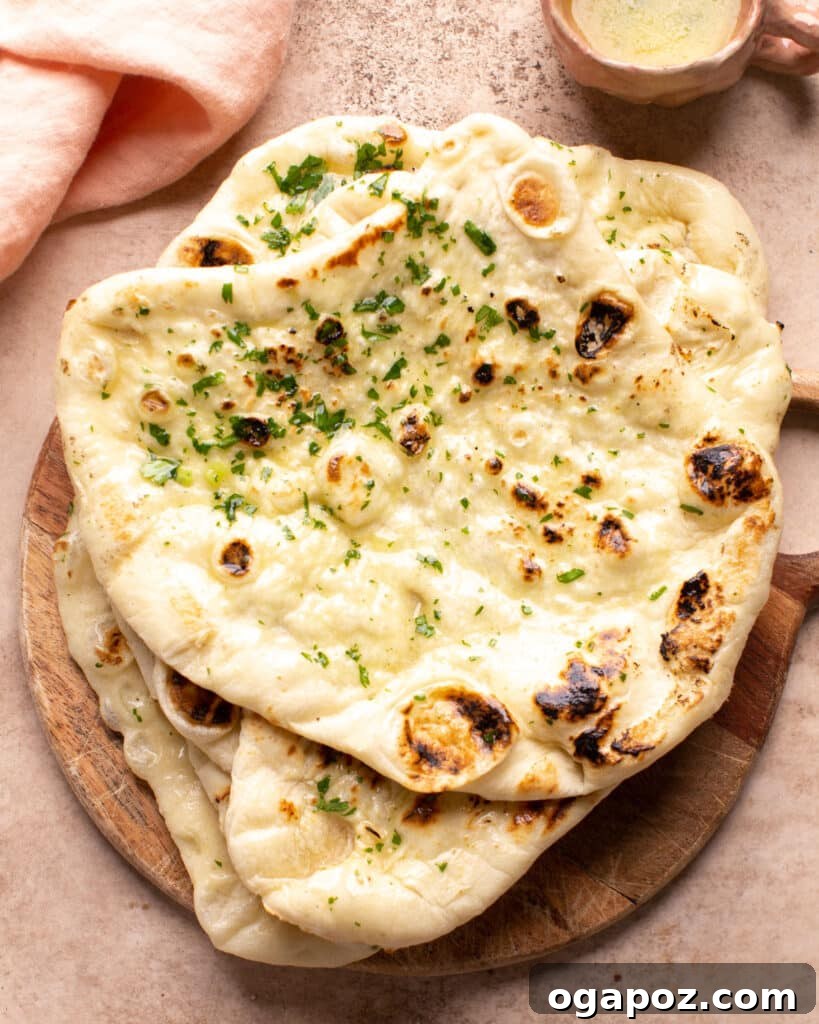 Fresh naan brushed with melted butter on a cutting board