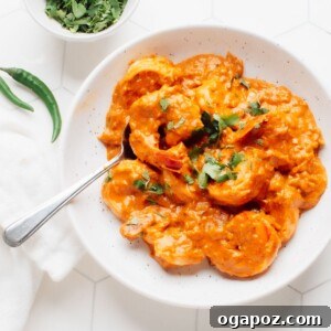 A serving bowl with shrimp korma with cilantro on top and a bowl of cilantro on the side.