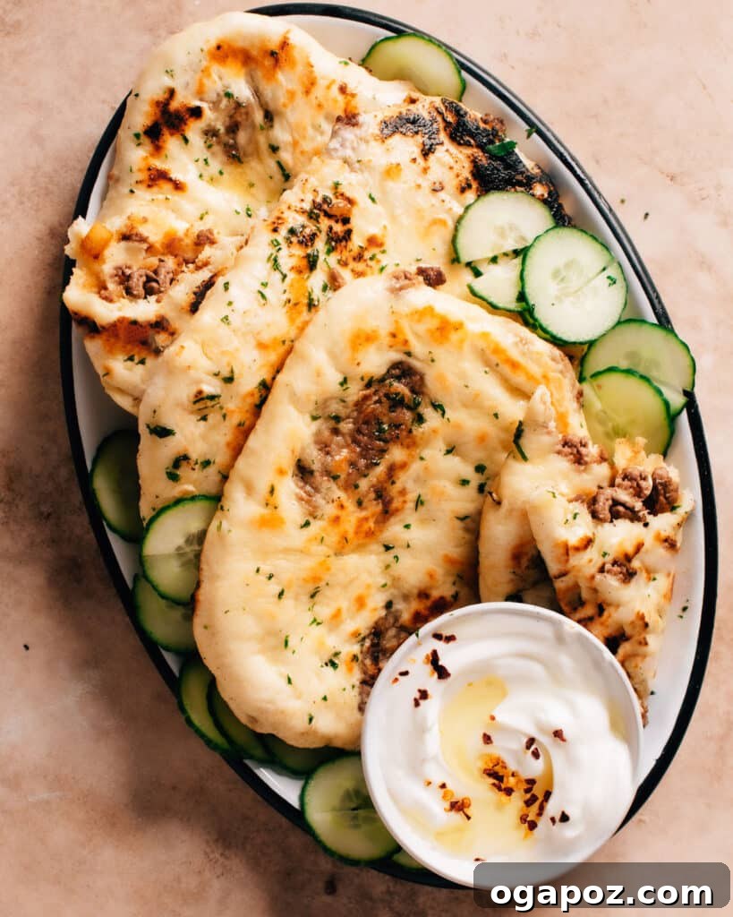 Spiced Keema Naan: Pillowy Flatbreads Bursting with Flavor 2 Delicious plate of fluffy keema naans served with thin slices of cucumber and a creamy dip, ready to be enjoyed.