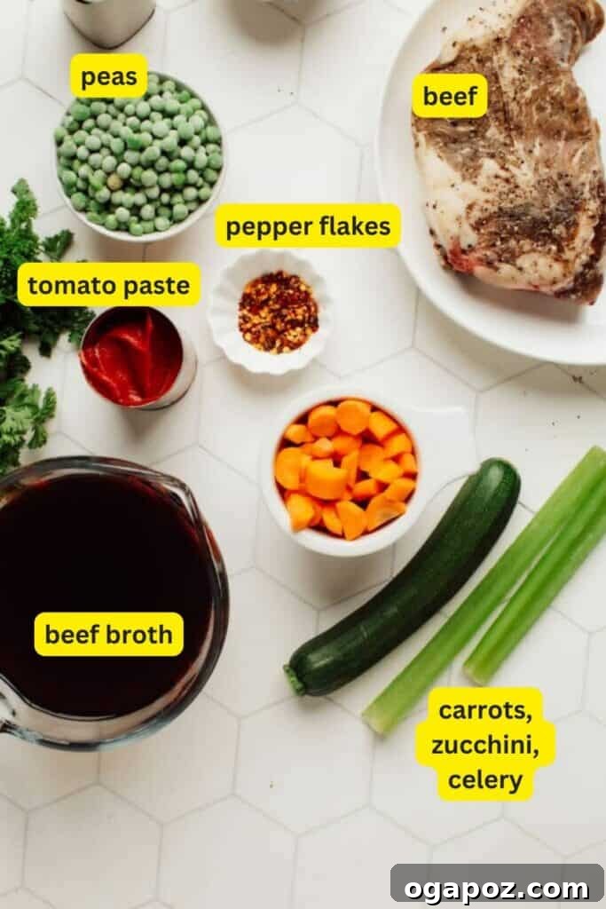 Grandma's Tender Beef and Vegetable Soup 3 A selection of fresh ingredients laid out on a kitchen counter, including beef chuck roast, onions, celery, carrots, zucchini, tomato paste, and herbs, ready for making Beef Vegetable Soup.