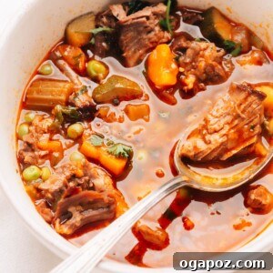 Close up photo of a spoonful of beef vegetable soup, showcasing the tender beef and colorful vegetables in a rich broth.