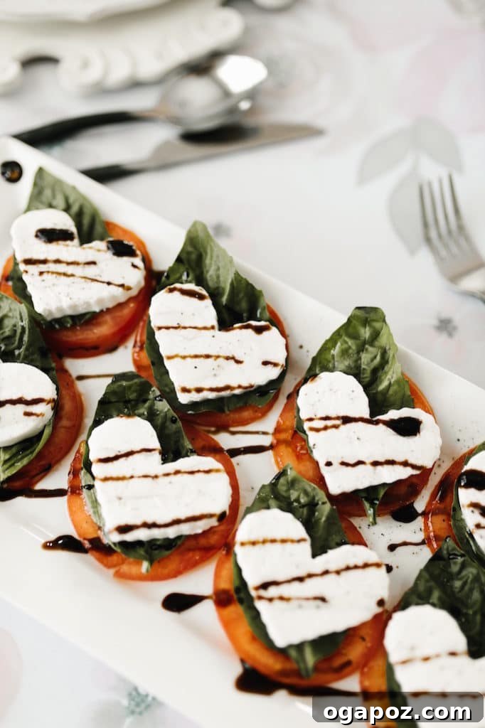 14+ Effortless Valentine's Day Family Feasts 17 A beautifully presented plate of Heart-shaped Caprese Salad, featuring fresh tomatoes, mozzarella, and basil leaves.