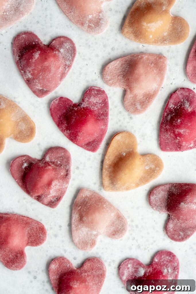 14+ Effortless Valentine's Day Family Feasts 12 Beautiful Beet Heart Ravioli, filled with ricotta and thyme, arranged on a white marble background.
