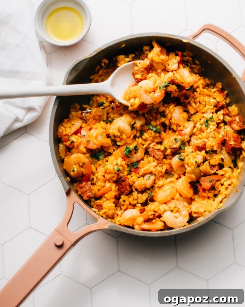 14+ Effortless Valentine's Day Family Feasts 13 Vibrant Chorizo Paella with shrimp and chicken in a large pan, with a serving spoon.