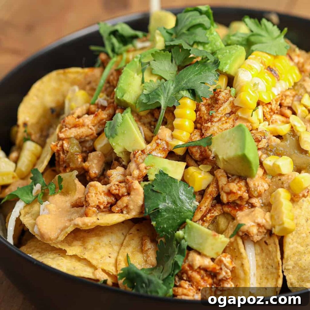 15 Easy Game Day Nachos Crowd Favorites 16 Loaded Chicken Enchilada Nachos served in a black bowl, rich with sauce and toppings.