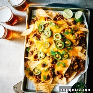 15 Easy Game Day Nachos Crowd Favorites 17 Game Day Nachos on a baking sheet with glasses of beer, representing a classic approach.