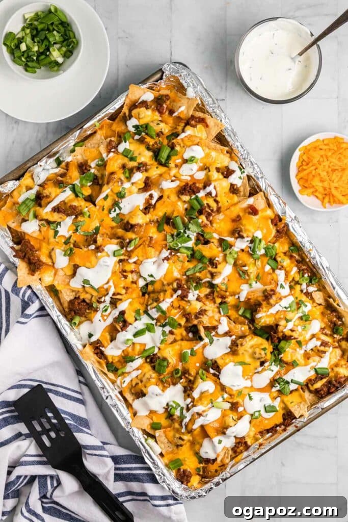 15 Easy Game Day Nachos Crowd Favorites 9 Top-down view of chili nachos in a sheet pan, loaded with toppings.