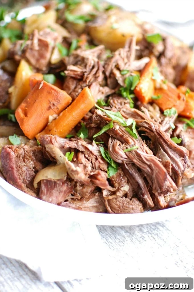 Crockpot Chuck Roast surrounded by tender carrots and potatoes, ready to be served.
