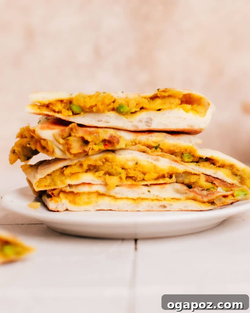 Stuffed Potato Naan 9 Side view of a half-cut aloo naans with visible filling, stacked on a plate.