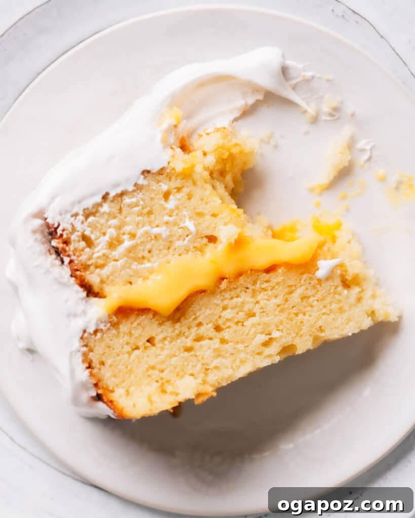 Zesty Lemon Curd Delight 4 A close-up of a delightful slice of lemon curd cake, showcasing perfectly defined layers of lemon cake, vibrant lemon curd filling, and ethereal white frosting. A fork has just taken a bite.