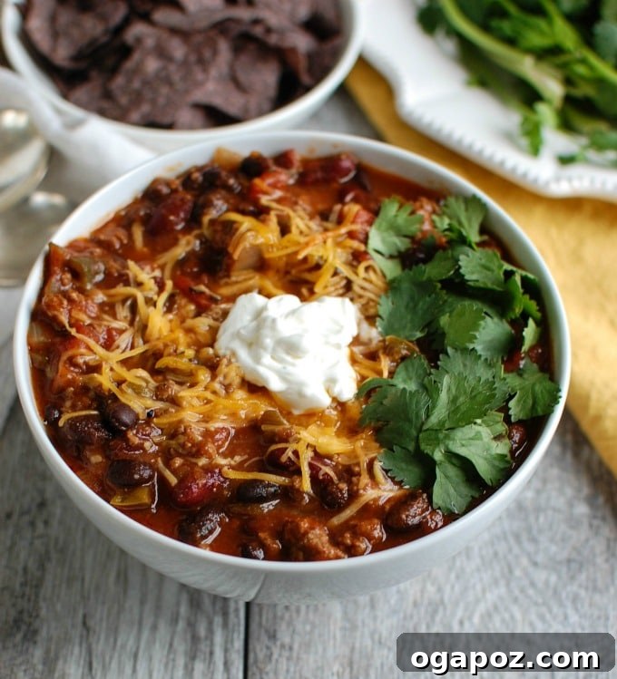 A bowl of Beef and Bean Chili served in a white bowl with toppings