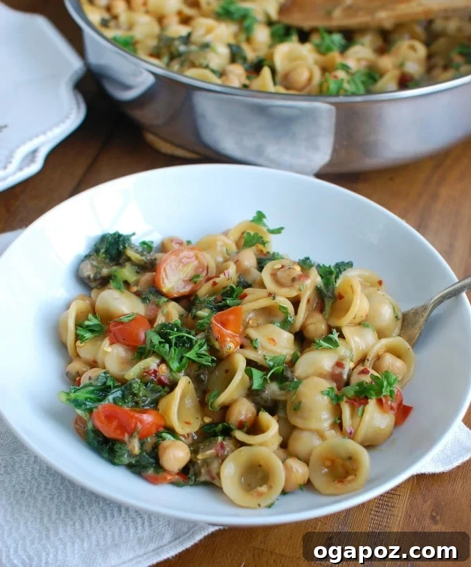 Effortless One-Pot Chickpea Kale Pasta 6 A serving of One Pot Chickpea Kale Pasta in a bowl, with a spoon ready to scoop, highlighting the creamy texture.