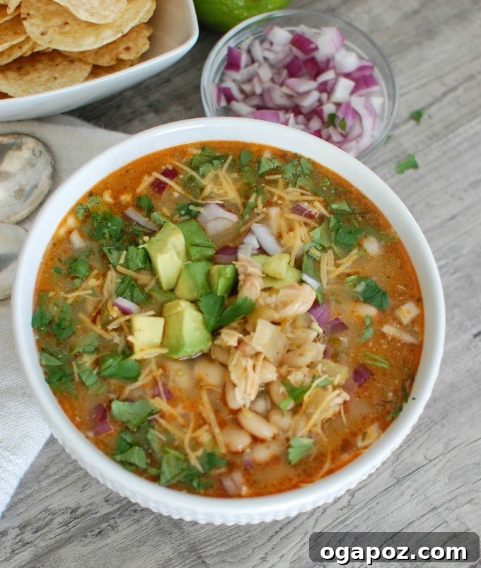 Velvety Slow Cooker White Chicken Chili 4 A bowl of Slow Cooker White Chicken Chili, ready to be served, with a spoon.