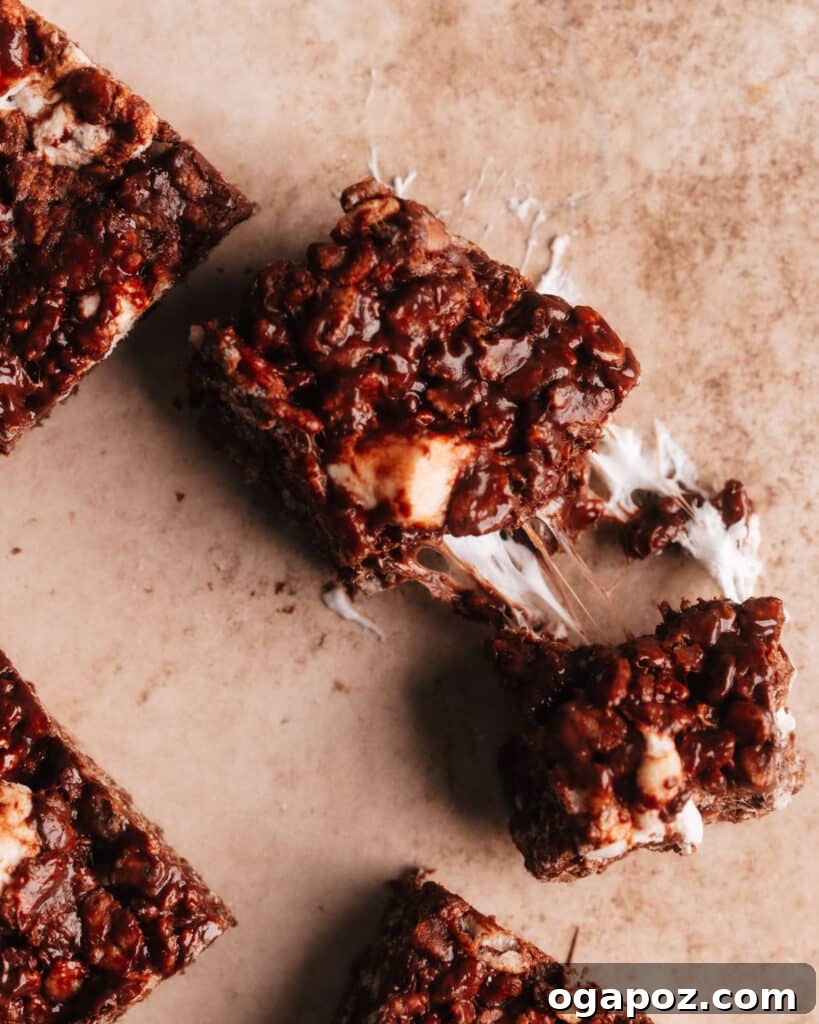 Chocolate rice krispie treat cut into 2 pieces, revealing the gooey melted marshmallows and chocolate chips in its texture.