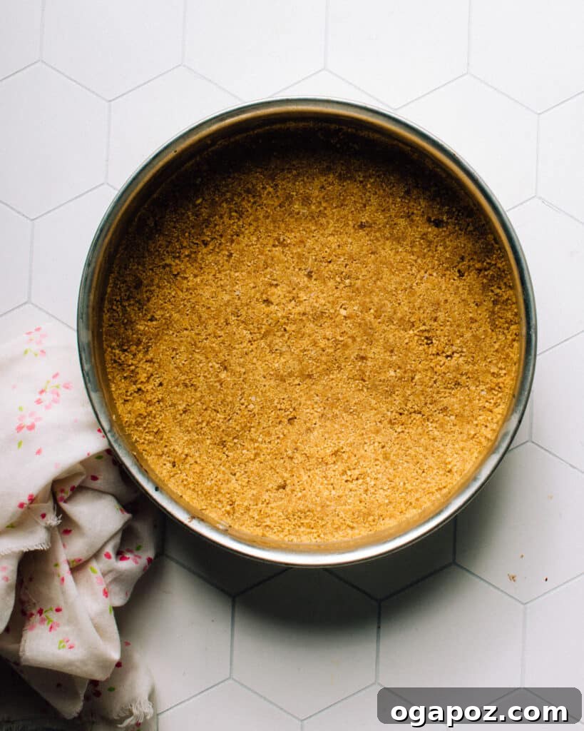 Colorful Easter Egg Cheesecake Chill 5 A springform pan with a perfectly pressed graham cracker crust forming the base and extending up the sides, ready for the cheesecake filling. The crust is evenly distributed and packed tightly.