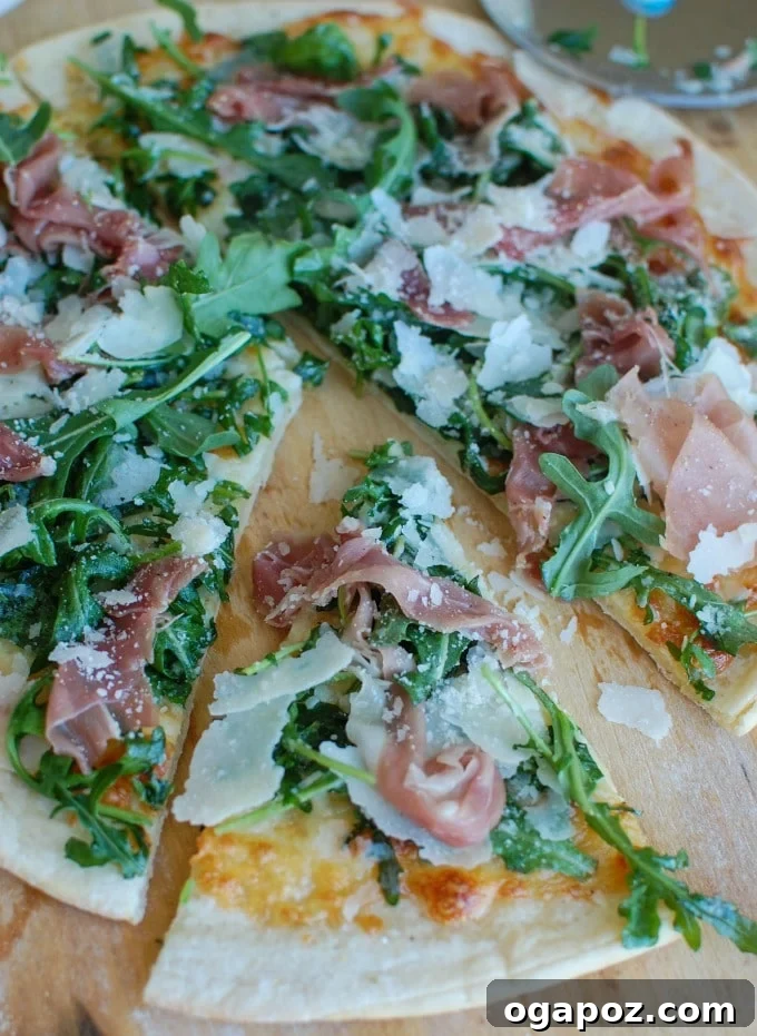 Gourmet Prosciutto Arugula Pizza 3 A slice of Prosciutto Arugula Pizza being lifted from the board, showing the melted cheese and fresh arugula.