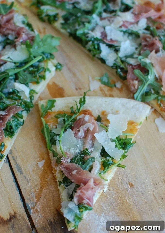 Gourmet Prosciutto Arugula Pizza 4 A whole Prosciutto Arugula Pizza, freshly baked and topped, on a wooden board.