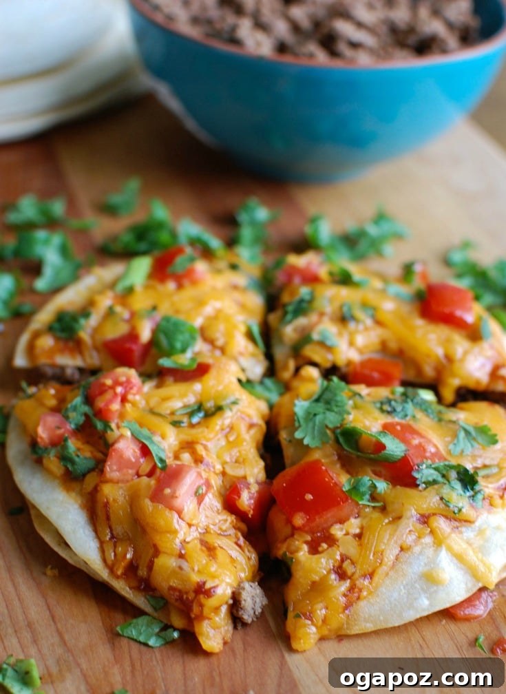 Four finished Mexican Pizzas on a baking sheet, garnished with cilantro and tomatoes, ready to be enjoyed.