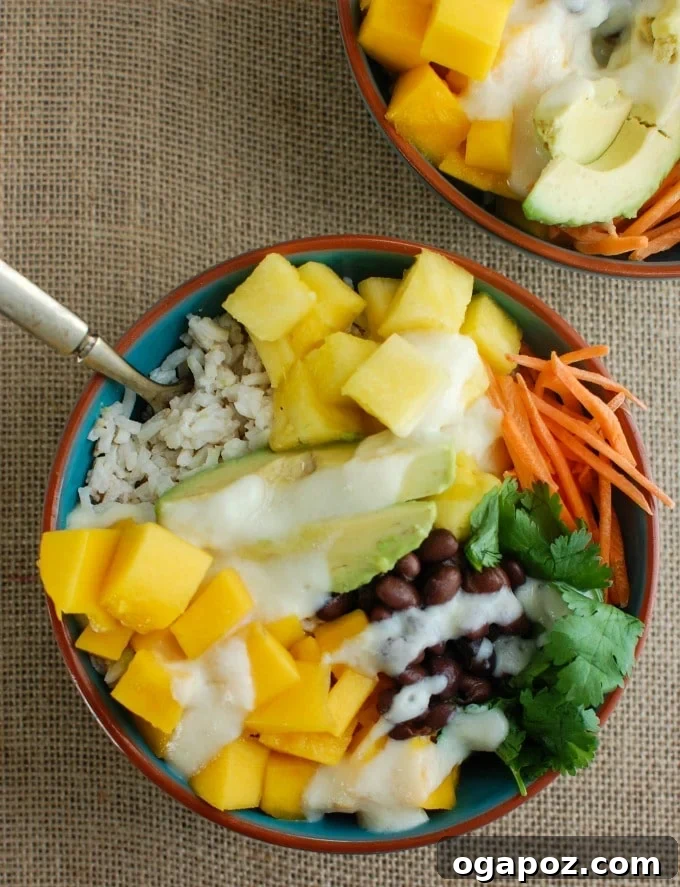 Tropical Coconut Rice Bliss 2 A vibrant Tropical Coconut Rice Bowl in a blue bowl, filled with coconut rice, mango, pineapple, black beans, avocado, and cilantro, drizzled with a creamy pineapple dressing.