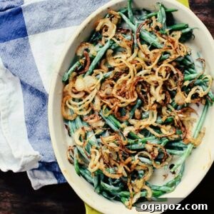 Green bean casserole with fried onions, bubbling hot from the oven and garnished with fresh herbs.