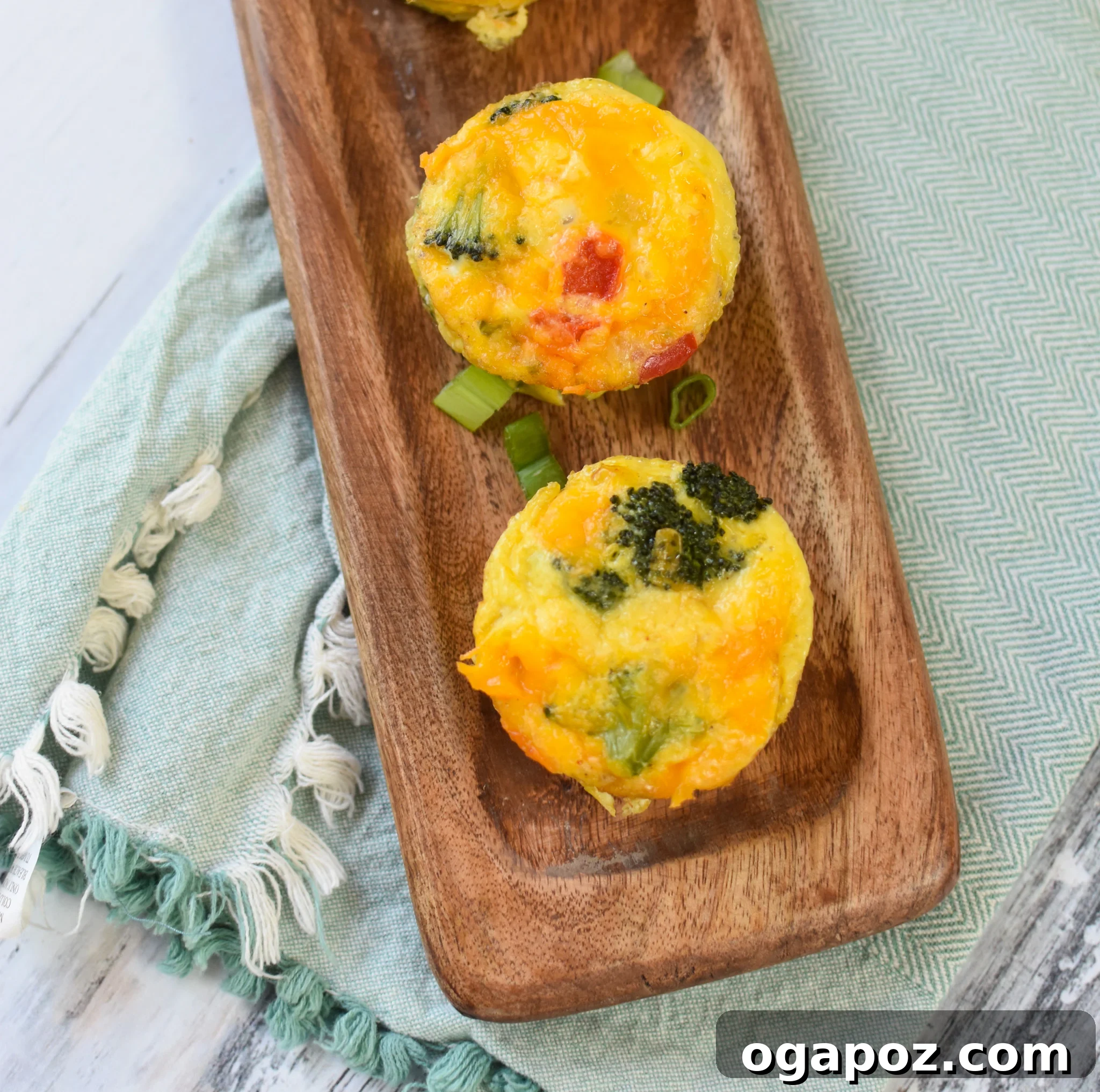 Cheesy Broccoli Bites 2 Broccoli Cheddar Cups on a rustic cutting board, showcasing their golden-brown edges and vibrant green broccoli.