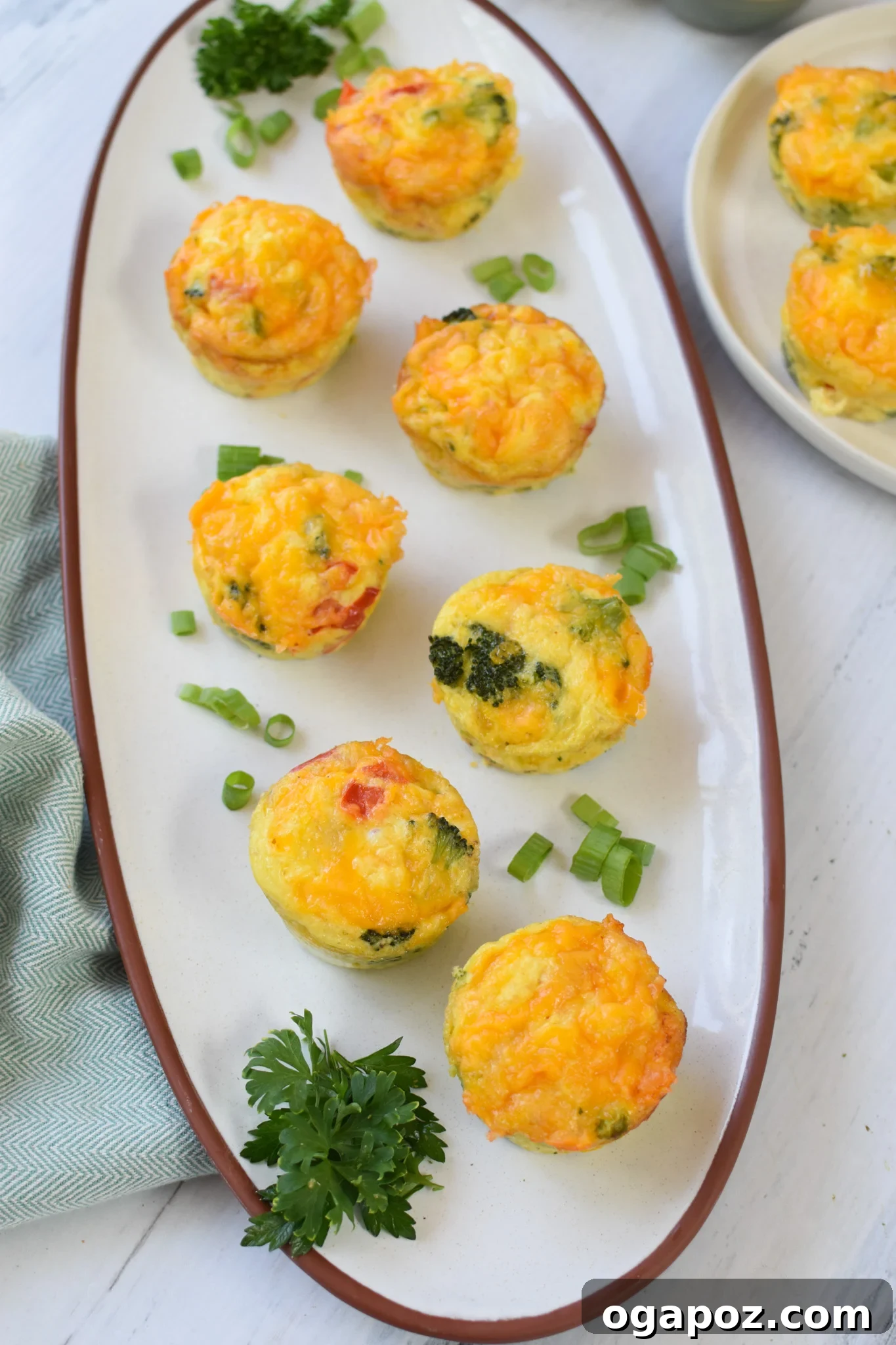 Cheesy Broccoli Bites 3 A close-up view of several golden-brown Broccoli Cheddar Cups arranged artfully on a white platter, highlighting their fluffy texture.