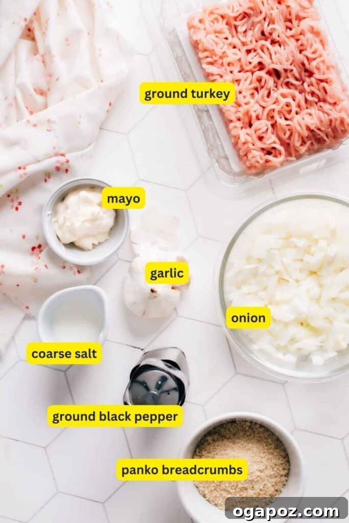 Flawless Air Fryer Turkey Burgers 5 Ingredients for turkey burgers laid out on a white kitchen countertop, including ground turkey, slices onions, mayo, salt, pepper and panko breadcrumbs.