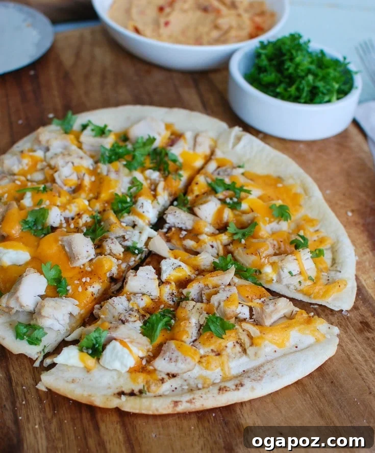 Savory Chicken Feta Cheddar Pita Pizza 2 Delicious Chicken Feta Cheddar Pita Pizza on a rustic cutting board, garnished with fresh parsley.