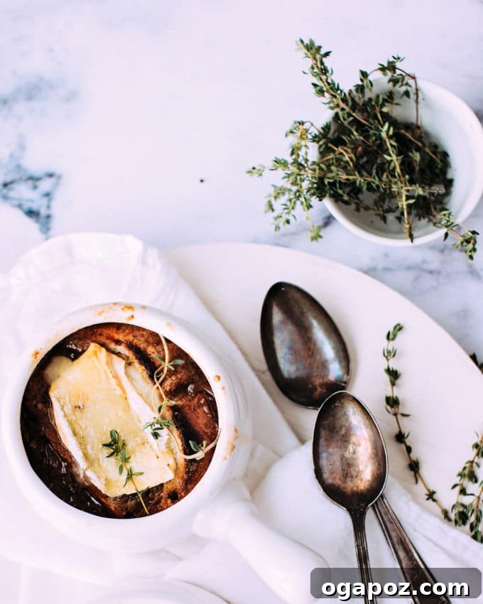 French Onion Soup with Golden Brie Crowns 4 French Onion Soup being ladled into an oven-safe crock, with a baguette slice and brie waiting to be broiled.