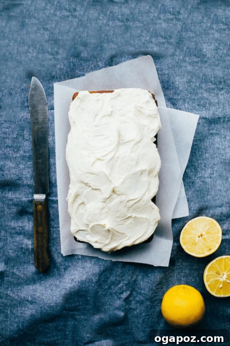 Sunshine Lemon Loaf 7 A beautifully decorated Lemon Pound Cake, sliced and presented with a garnish of lemon zest, fresh mint, and berries on a white plate, ready to be enjoyed.