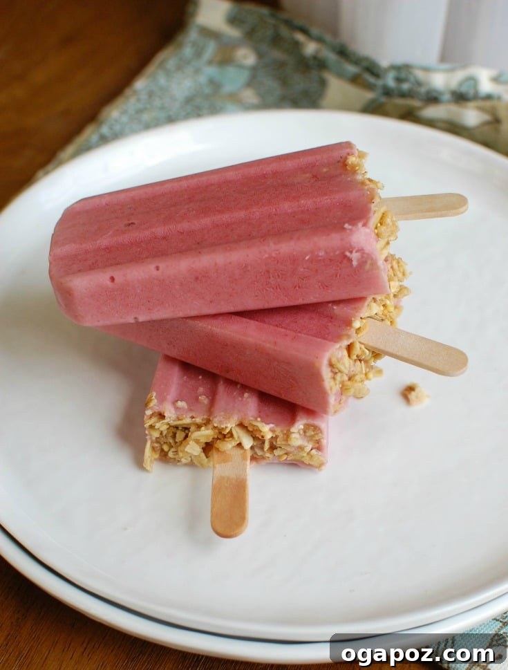 Strawberry Banana Yogurt Swirl Pops 5 A selection of colorful Strawberry Banana Yogurt Popsicles displayed on a white plate, ready for a cool treat.