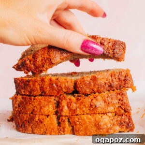 Perfectly Soft and Moist Banana Zucchini Bread 5 A slice of Banana Zucchini Bread being lifted from a freshly baked loaf.
