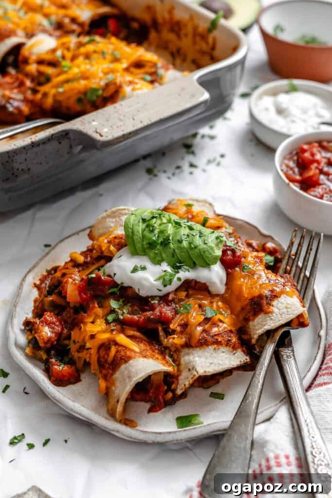 Effortless Vegetarian Enchiladas 8 Close-up of Easy Vegetarian Enchiladas in a casserole dish, garnished with fresh avocado and a dollop of sour cream.