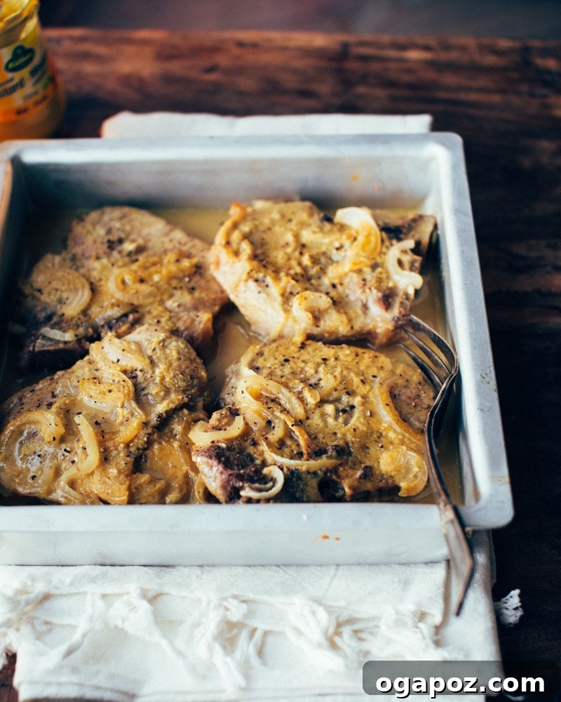 Golden Honey Mustard Pork Chops 2 Close-up of baked honey-mustard pork chops with caramelized onions in a baking dish