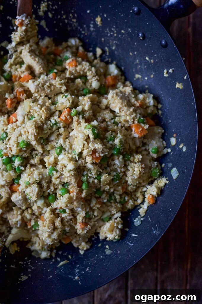Wholesome Meals in Minutes 15 15 Minute Cauliflower Chicken Fried Rice served in a white bowl with chopsticks.
