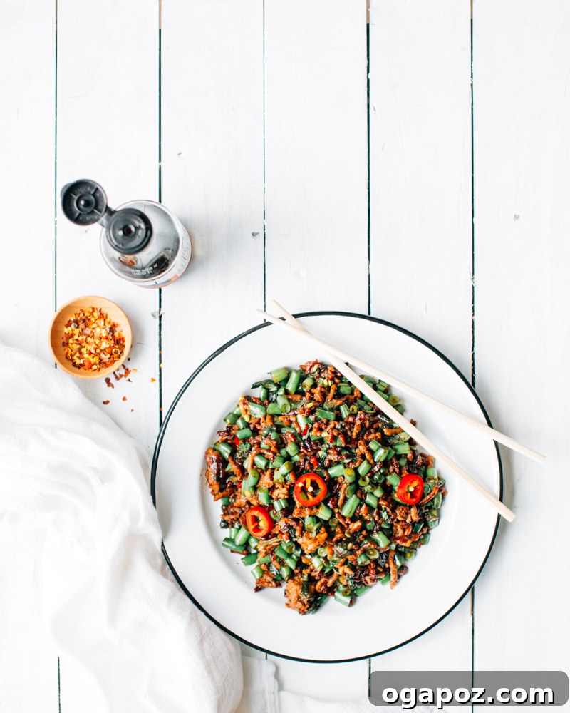 A vibrant plate of Thai Basil Pork stir-fry with a sunny-side-up fried egg on top, served with steamed rice, ready to be enjoyed.