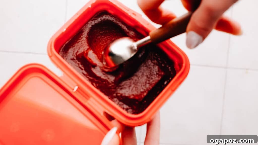 A bowl of vibrant red Gochujang sauce with a spoon, showing a popular chili paste often used as a Doubanjiang alternative.