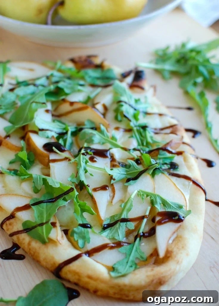 Gourmet Pear and Brie Flatbread 2 Delicious Pear and Brie Flatbread topped with fresh arugula and balsamic glaze, ready to serve as an elegant holiday appetizer.